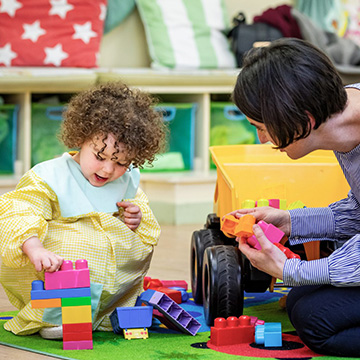 girl and teacher playing with duplo