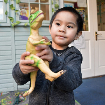 child holding a toy t-rex