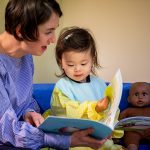 child and teacher reading a book