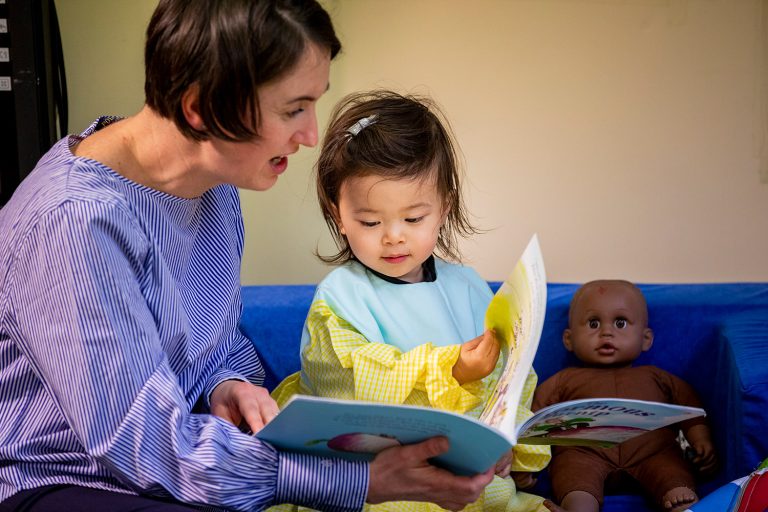 child and teacher reading a book
