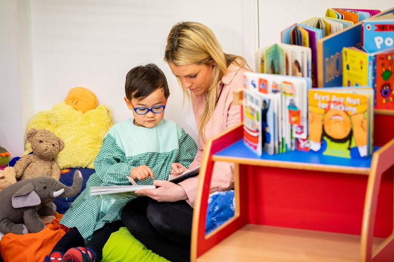 child and teacher reading together