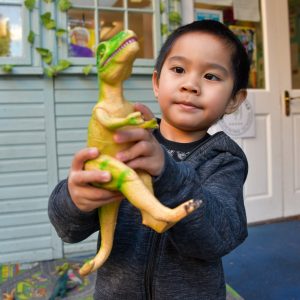 child holding a t-rex toy
