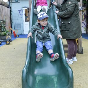 children going down a slide with teacher supervision