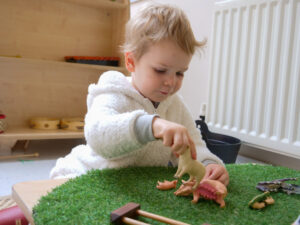 little boy playing with toy farmyard animals
